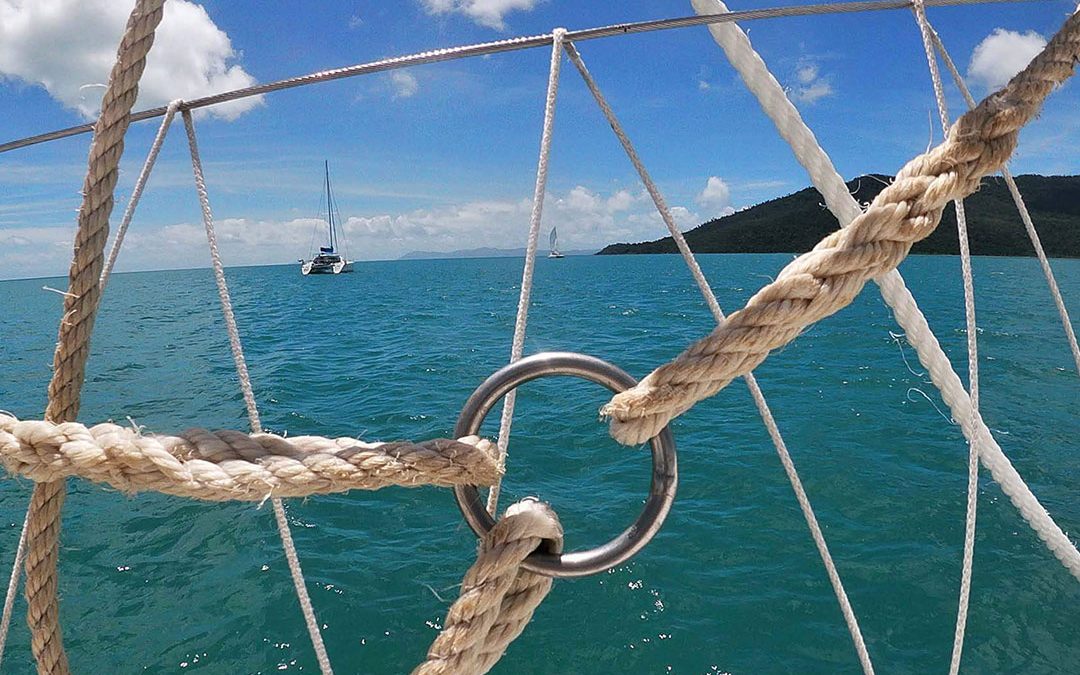 View of the water and sail boats through some ropes